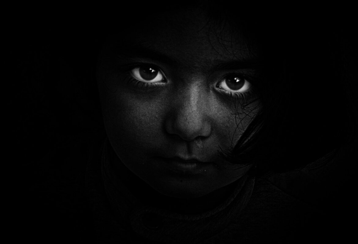 Intense black and white portrait of a child with captivating eyes, evoking mystery and emotion.