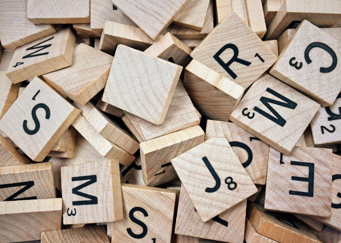 A collection of wooden Scrabble tiles with letters and numbers stacked randomly.