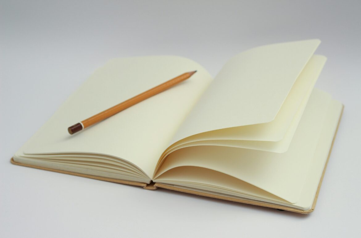 An open notebook with blank pages and a pencil, perfect for starting new ideas or journaling.